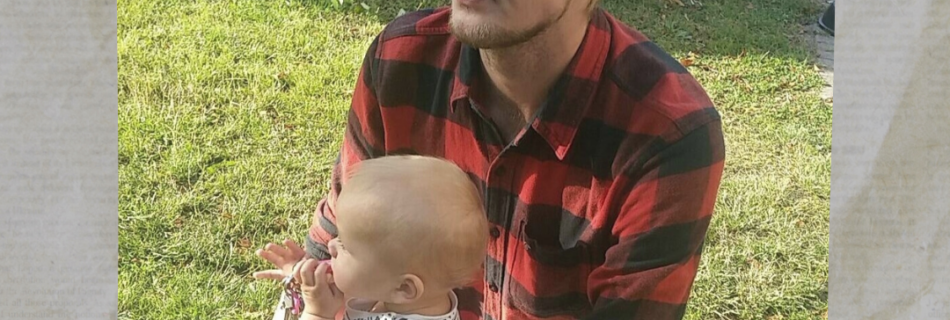Bild på Jesper Billung på en gräsmatta, iförd keps och rutig flanellskjorta tillsammans med sin son i spädbarnsålder.